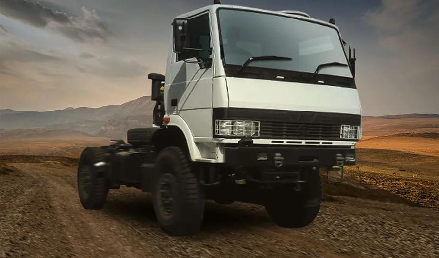 White Tata LPTA 715 off-road truck driving on a rugged dirt road with mountain backdrop
