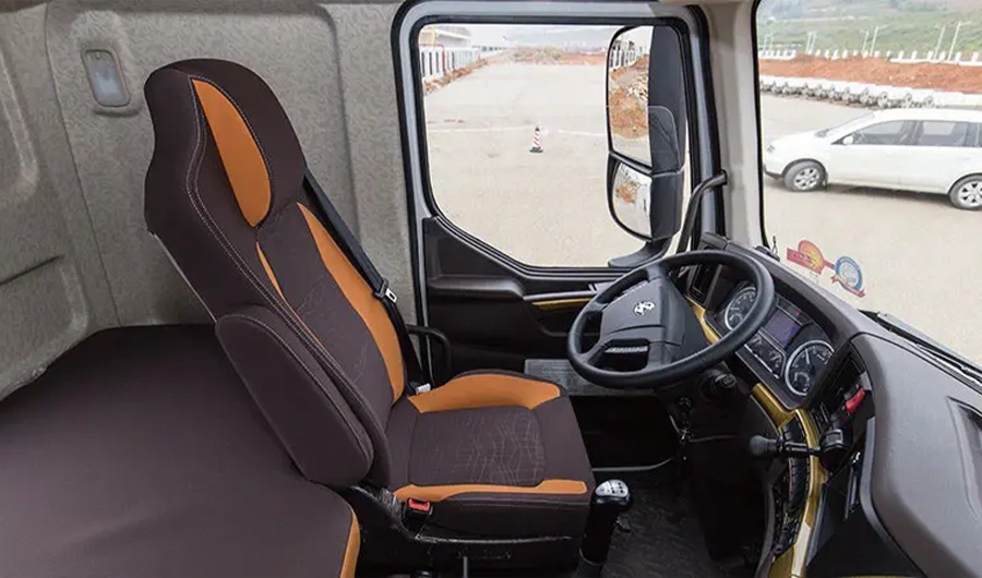 Chenglong Heavy-duty truck cab interior showing driver seat, sleeper bed, steering wheel, dashboard and side mirror