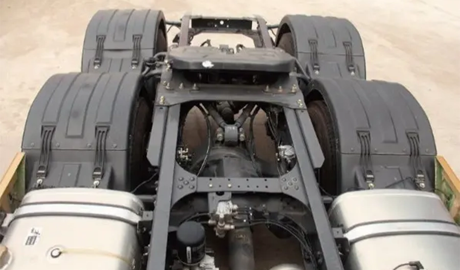 Heavy-duty truck chassis showing fifth wheel coupling, dual rear axles, fuel tanks and frame components