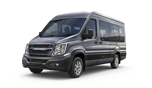 hree-quarter front profile of a metallic grey Force Motors Urbania van parked in front of commercial office buildings