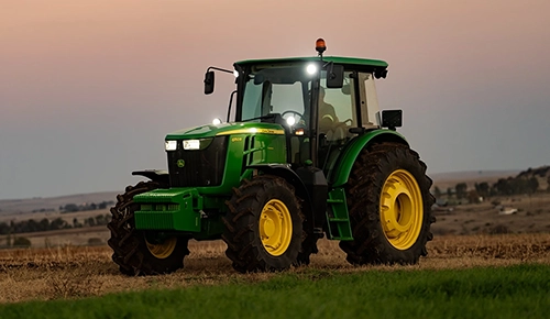 John Deere 6B Series tractor parked in an agricultural field at dusk