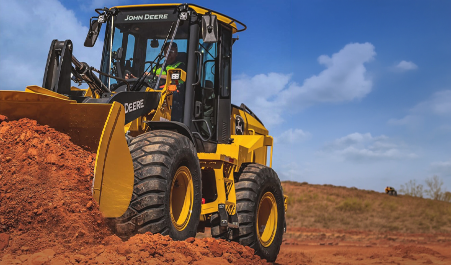 John Deere wheel loader carrying a full bucket of earth at a construction and earthmoving site