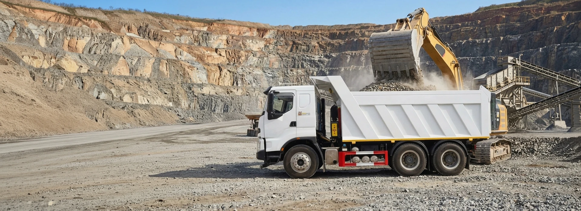 White heavy-duty 6x4 tipper dump truck operating in a quarry loading area