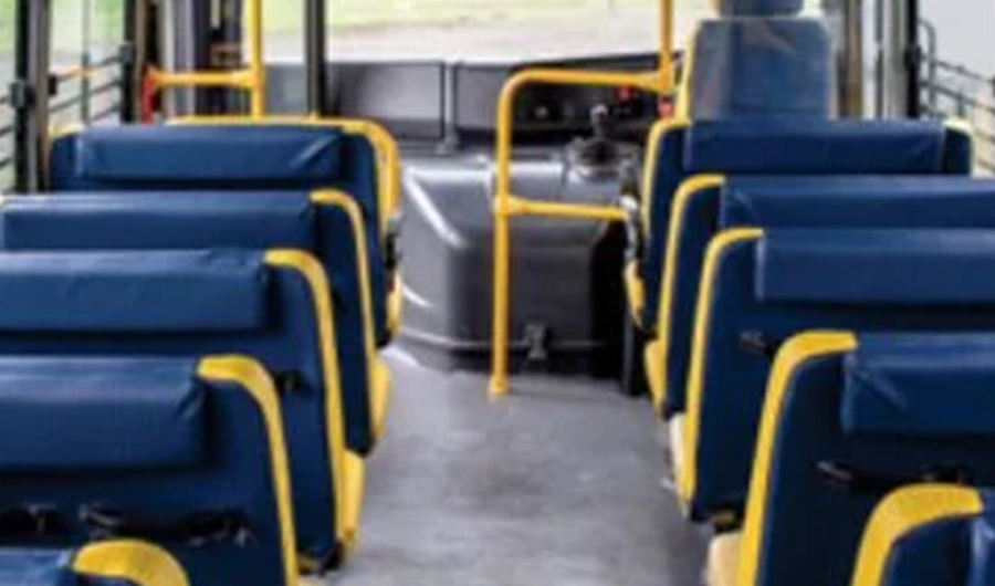 Force Monobus school bus interior with rows of blue passenger seats, central aisle and yellow safety handrails