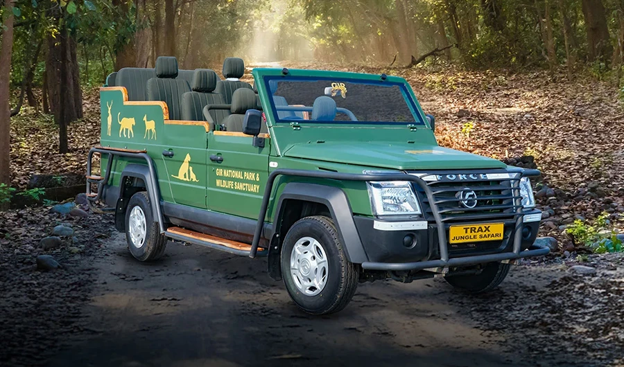 Jungle green Force Trax open-top safari vehicle with multi-row elevated seating, heavy front brush guard, and side step rails on a forest trail