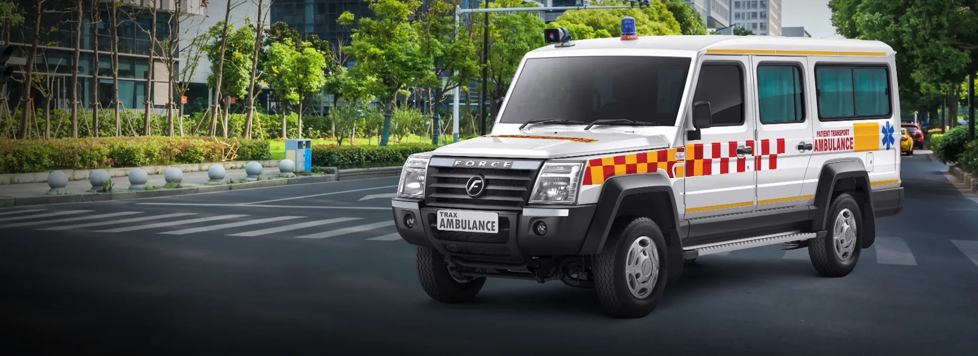 White Force Trax patient transport ambulance featuring red and yellow checkered emergency decals, a roof-mounted beacon light, and tinted side windows on an urban road