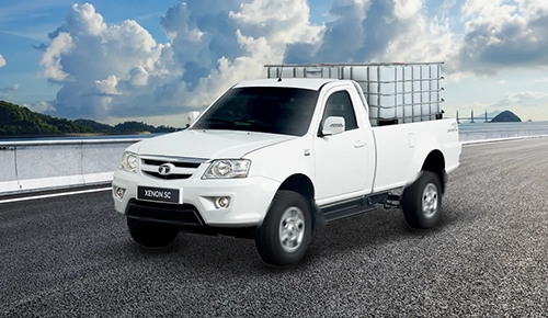 Front three-quarter view of a white Tata Xenon SC single cab bakkie loaded with a large liquid container driving on an asphalt road