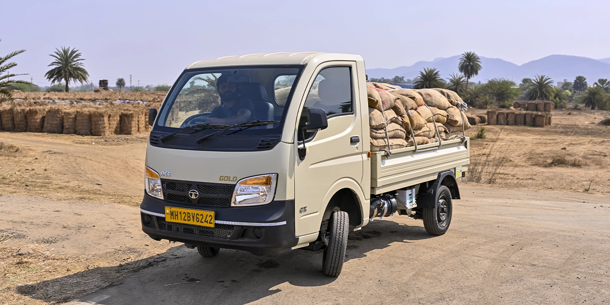 Beige Tata Ace Gold mini truck loaded with grain sacks driving on a dirt road