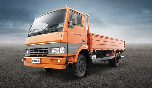 Orange and grey Tata LPT 709 Ex dropside flatbed truck viewed from a low front-three-quarter angle
