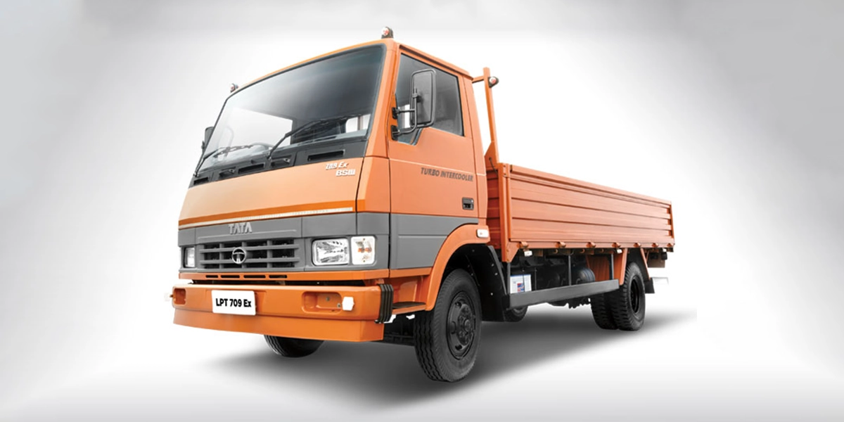 Orange Tata LPT 709 EX light commercial truck featuring a drop-side cargo body and a turbo intercooler engine, shown in a studio shot.