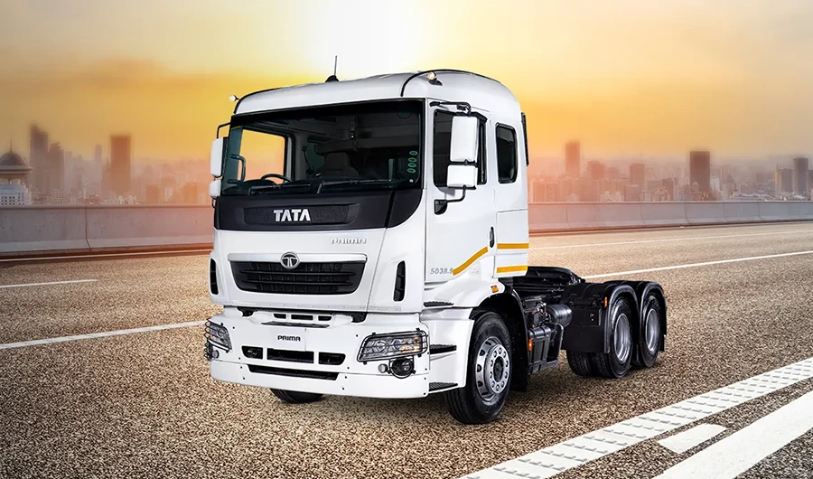 White Tata Prima 5038.S heavy-duty commercial truck parked on a highway with a city skyline in the background at sunset