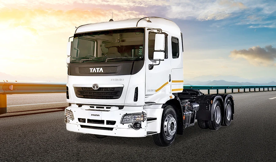 A white Tata Prima heavy-duty truck tractor parked on a paved highway next to a guardrail during sunrise or sunset.