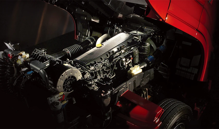 Tilted red cab revealing the heavy-duty diesel engine block and components in the chassis bay.