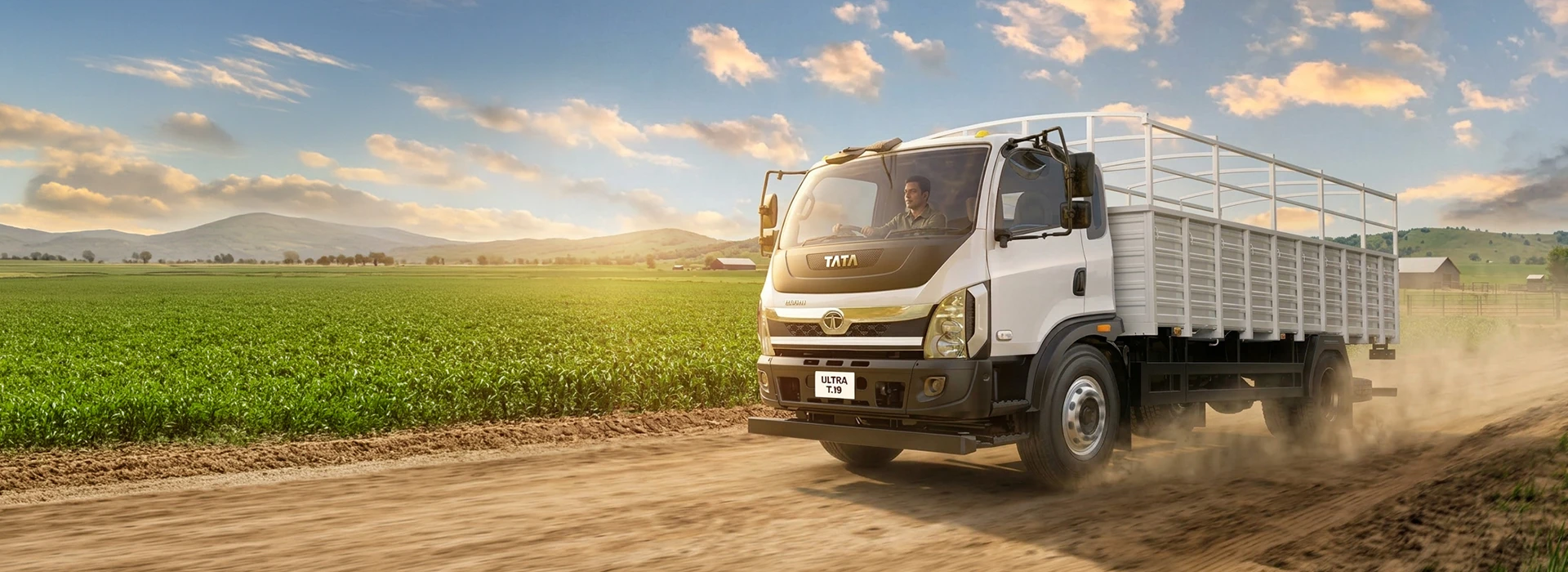 White Tata Ultra T.19 cargo truck driving on a dirt road alongside agricultural fields desktop banner