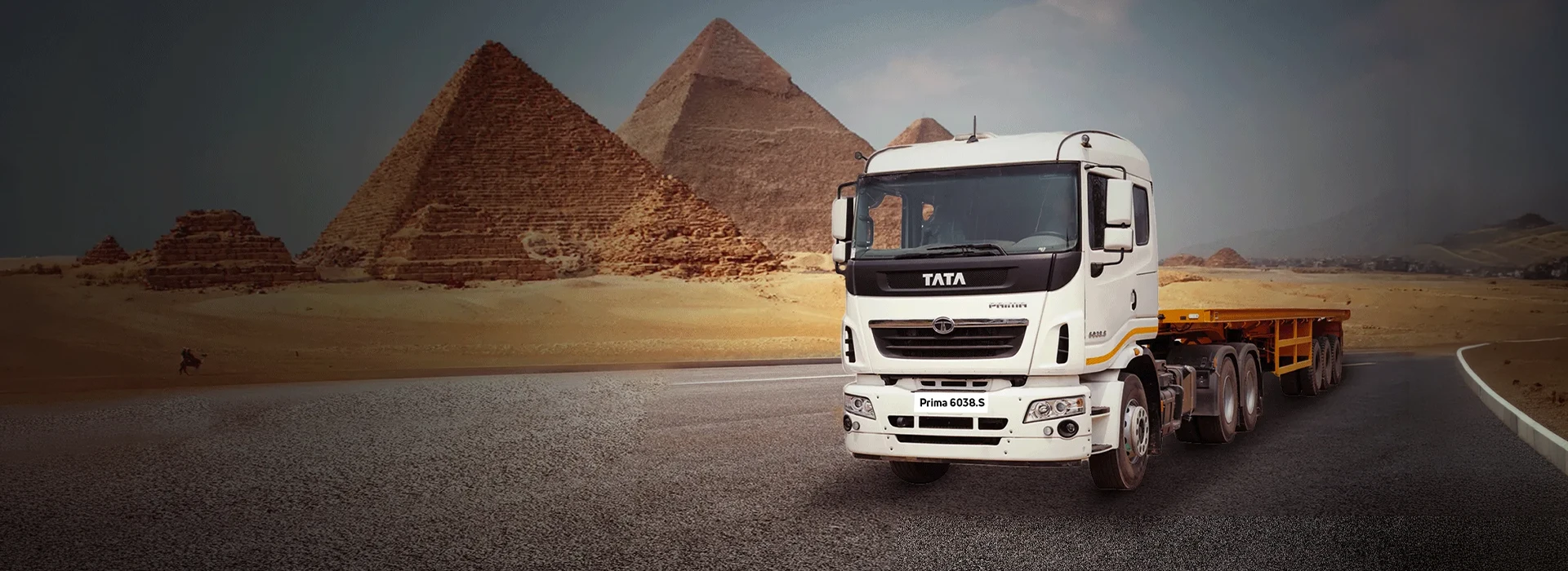White Tata Prima 6038.S tractor trailer on a highway with ancient pyramids background desktop banner