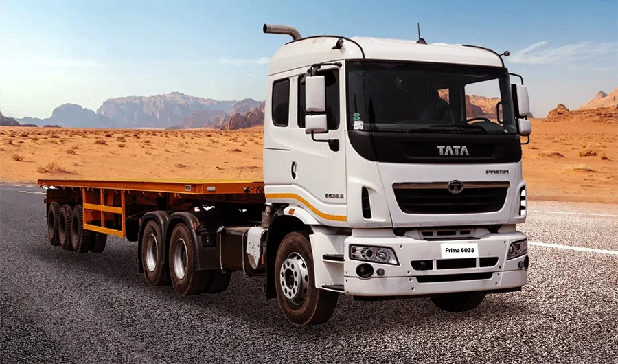 White Tata Prima 6038.S tractor head with yellow flatbed trailer on a desert highway