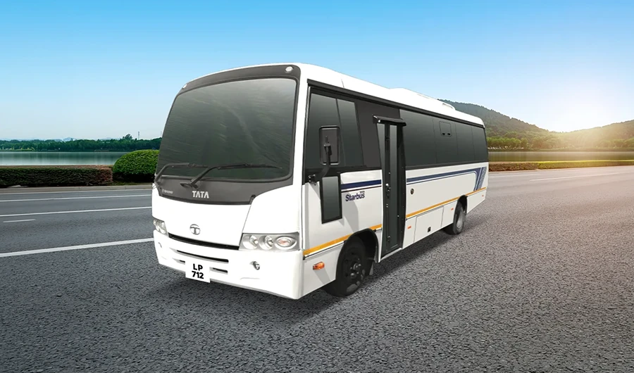White Tata LP 712 Starbus passenger bus parked on a paved road with tree-lined lake background