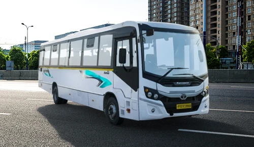 white Tata Starbus Ultra LPO 10.2/54 bus driving on a multi-lane city road with skyscrapers in the background