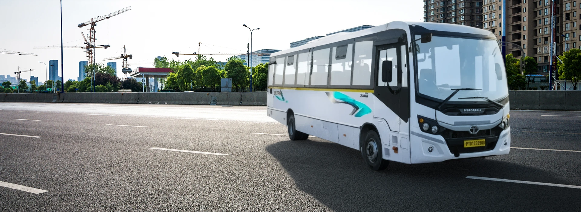 White Tata Starbus Ultra LPO 10.2/54 bus driving on a multi-lane city road with skyscrapers in the background