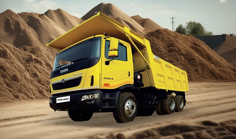 Yellow Tata Prima 2528.K tipper truck parked in front of aggregate sand stockpiles
