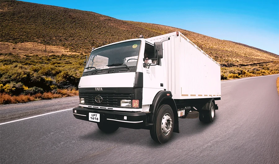 White Tata LPT 1618 container cargo truck driving along a mountain highway