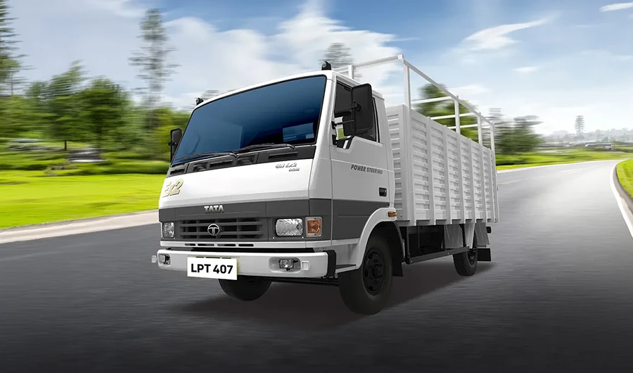 Front three-quarter view of white Tata LPT 407 truck driving past green landscape