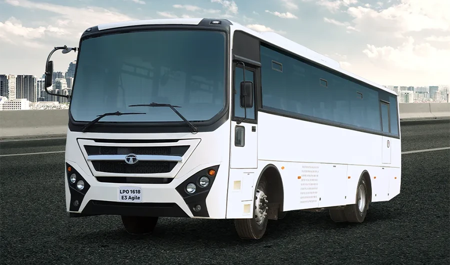 White Tata LPO 1618 Agile passenger bus driving on an open road along a mountain