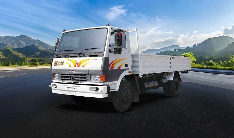 Tata LPT 1116 EX2 drop-side truck driving on asphalt road with mountain background