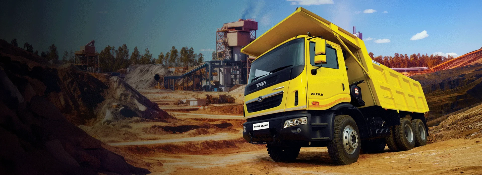 Yellow Tata Prima 2528.K heavy-duty tipper truck in front of an industrial mining plant