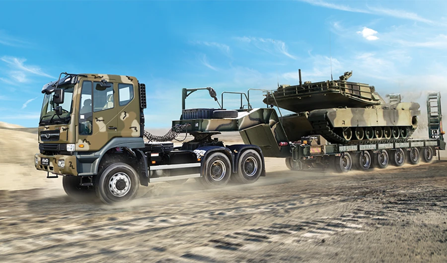 Camouflage Daewoo Novus military tractor truck hauling a tank on a heavy-duty lowbed trailer