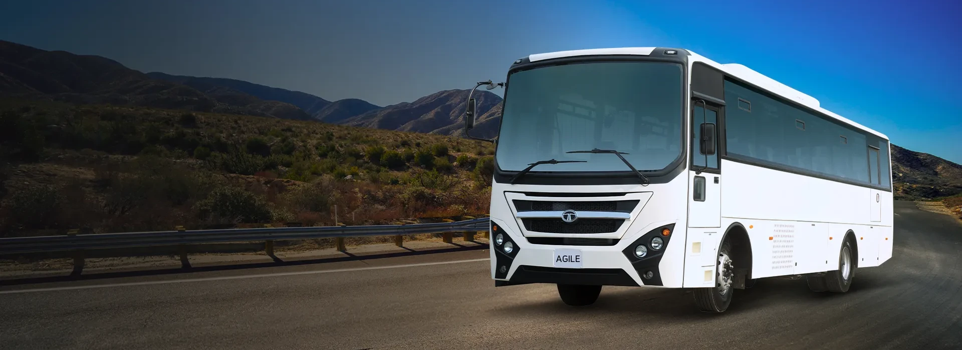 White Tata LPO 1618 Agile passenger bus driving on an open road along a mountain range