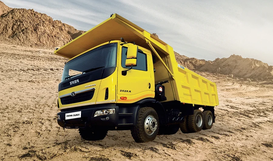 Yellow Tata Prima 2528.K heavy-duty tipper truck on rocky dirt quarry terrain