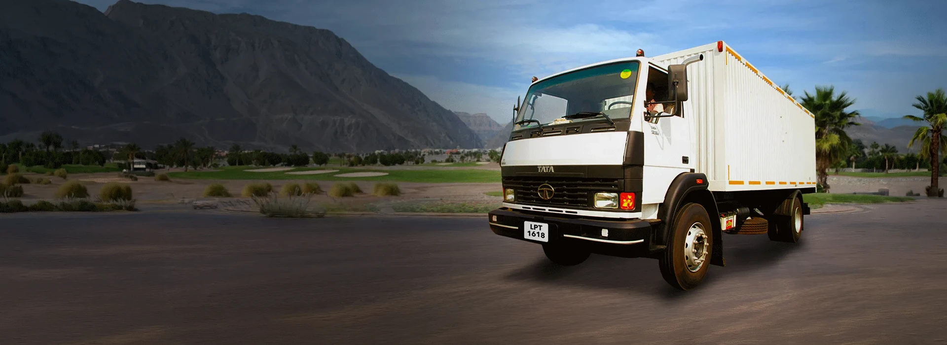 White Tata LPT 1618 closed container truck on a road against mountains desktop banner