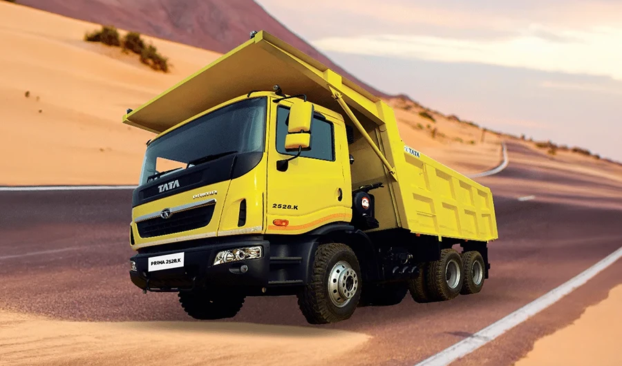 ellow Tata Prima 2528.K tipper truck on a road through desert sand dunes