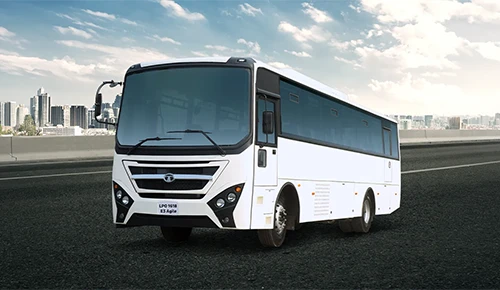 White Tata LPO 1618 E3 Agile passenger bus driving on a highway with a city skyline background