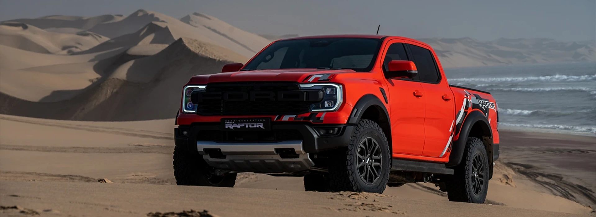 Ford Ranger Raptor low angle shot standing in beach with the ocean in the background