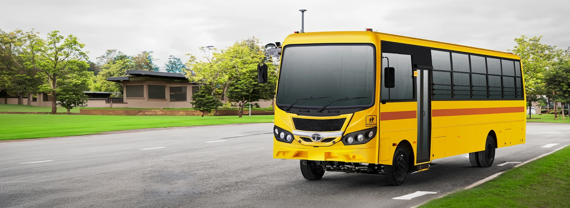 Yellow Tata CityRide school bus parked on a road next to a park area