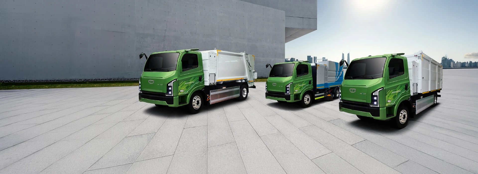 Lineup of green Daewoo Gixen eco-friendly municipal trucks including a garbage compactor, street sweeper, and refuse container truck parked on a paved plaza