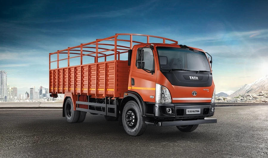Orange Tata T.12 Ultra commercial truck featuring a high-sided cargo body on a road under a blue sky