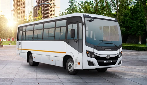 White Tata LP 913 52 passenger bus showcased on a paved city plaza with modern high-rise buildings in the background.
